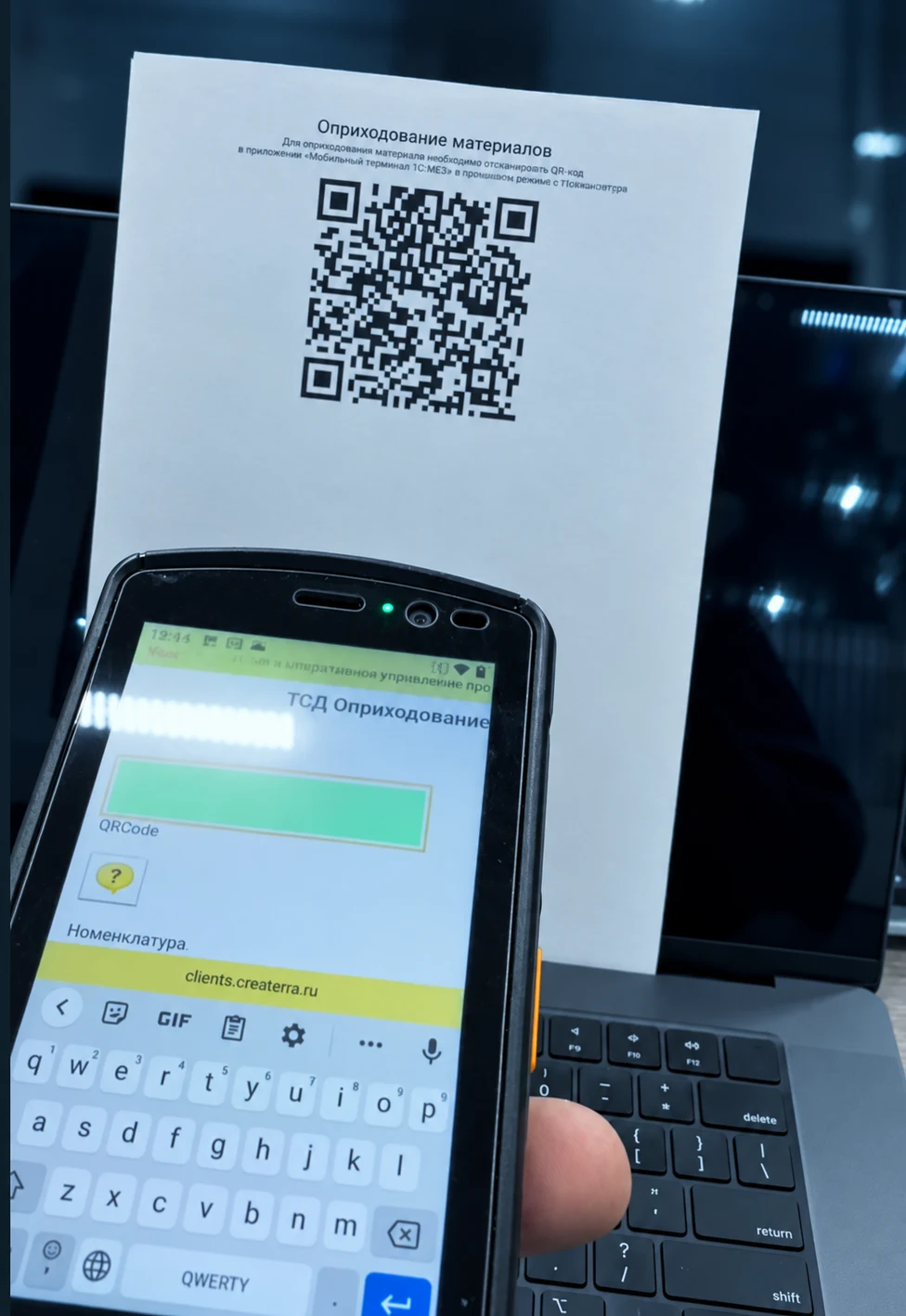 Терминал сбора данных с формой оприходования материалов рядом с QR-кодом для приёмки на склад.